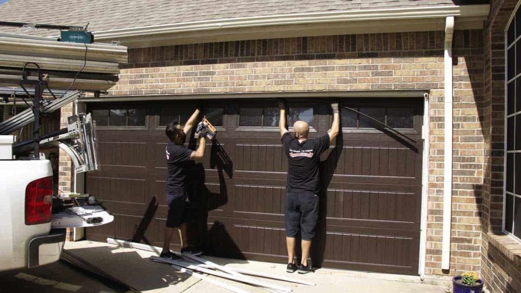 Two technicians installing a garage door, showcasing professional Garage Door Installation services.